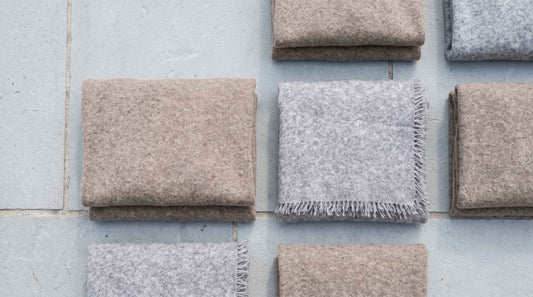 Folded undyed Himalayan cashmere in natural tones — a Lumusae gift flat-lay