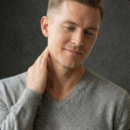 Man wearing a gray sweater against a dark background