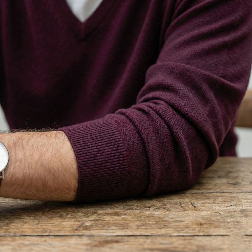 Close-up of a person wearing a maroon sweater with a blurred background