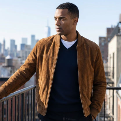 Man wearing a brown jacket on a rooftop with city skyline in the background