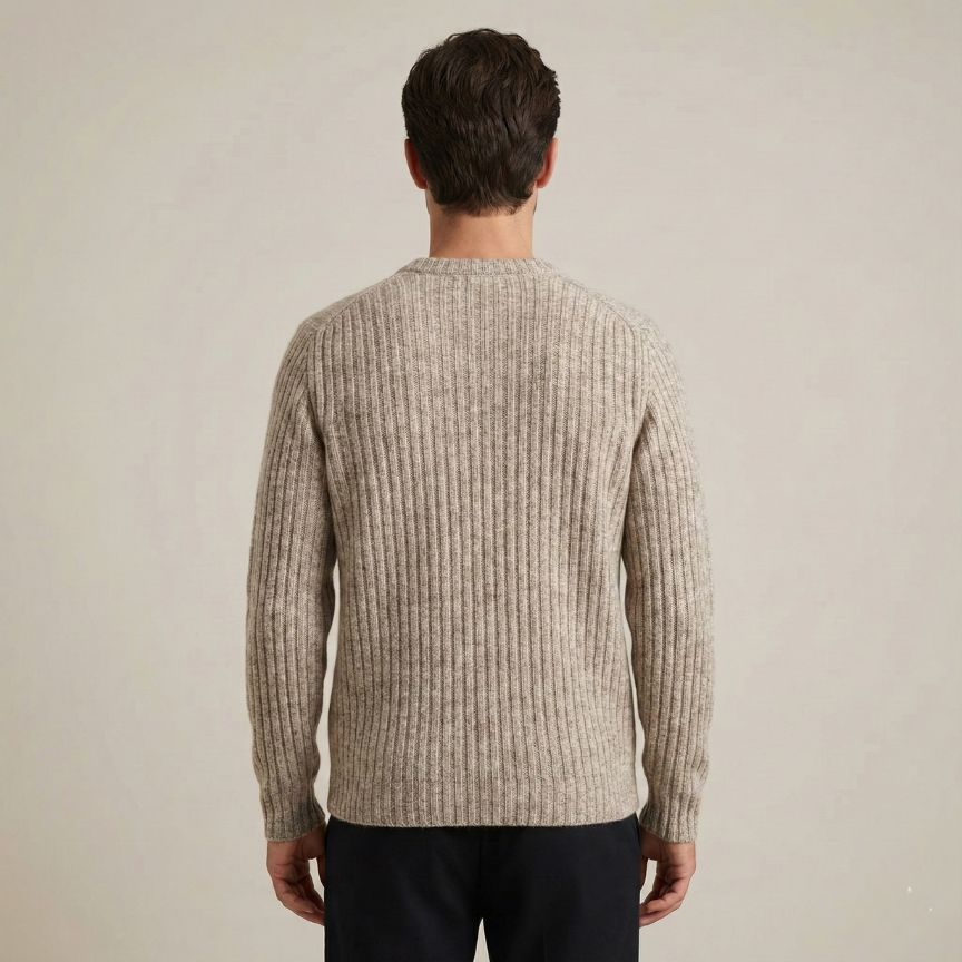 Man wearing a beige ribbed sweater against a plain background