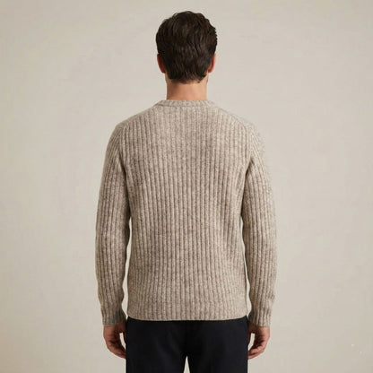 Man wearing a beige ribbed sweater against a plain background