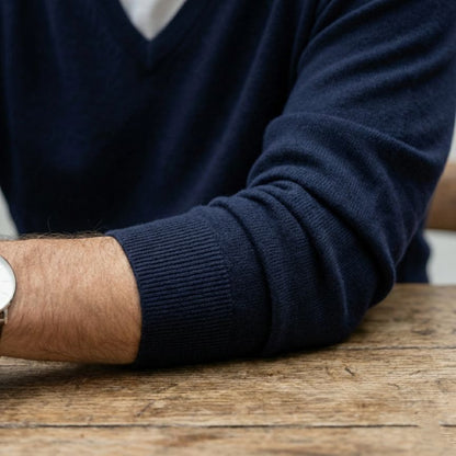 Person wearing a navy sweater with a wooden surface in the background