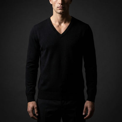Man wearing a black V-neck sweater against a dark background