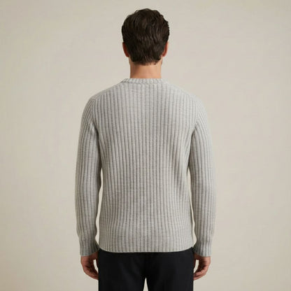 Man wearing a ribbed sweater against a plain background